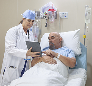 Healthcare provider talking to man in pre-op hospital room.