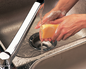 Primer plano de manos en un lavabo debajo del chorro de agua. Las manos están cubiertas de espuma de jabón.